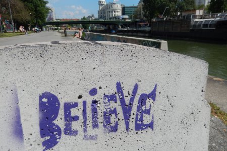 Graffiti des Wortes &quot;Believe&quot; - im Hintergrund der Donaukanal