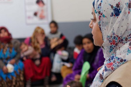 Im Vordergrund sieht man das Profil einer muslimischen Frau mit Kopftuch, im Hintergrund, der unscharf fotografiert ist, sind weitere Frauen zu erkennen.
