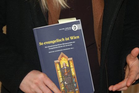 in Händen gehalten wird das Buch &quot;So evangelisch ist Wien&quot;