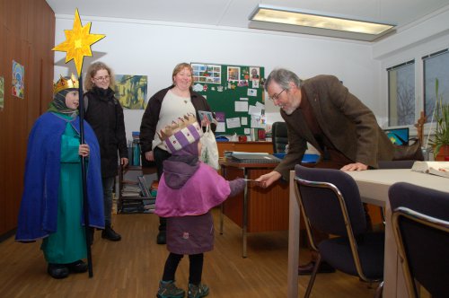 Sternsingerin Ruth übergibt Superintendent Hansjörg Lein eine Broschüre.