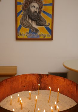 Kerzenlicht als Zeichen der lebendigen Hoffnung. Hinter der Feuerschale hängt ein von einem Insassen gefertigtes Bild mit dem Zuspruch: „Only God can judge me“. 