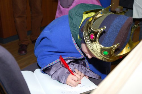 Sternsinger Jakob trägt sich ins Gästebuch ein.