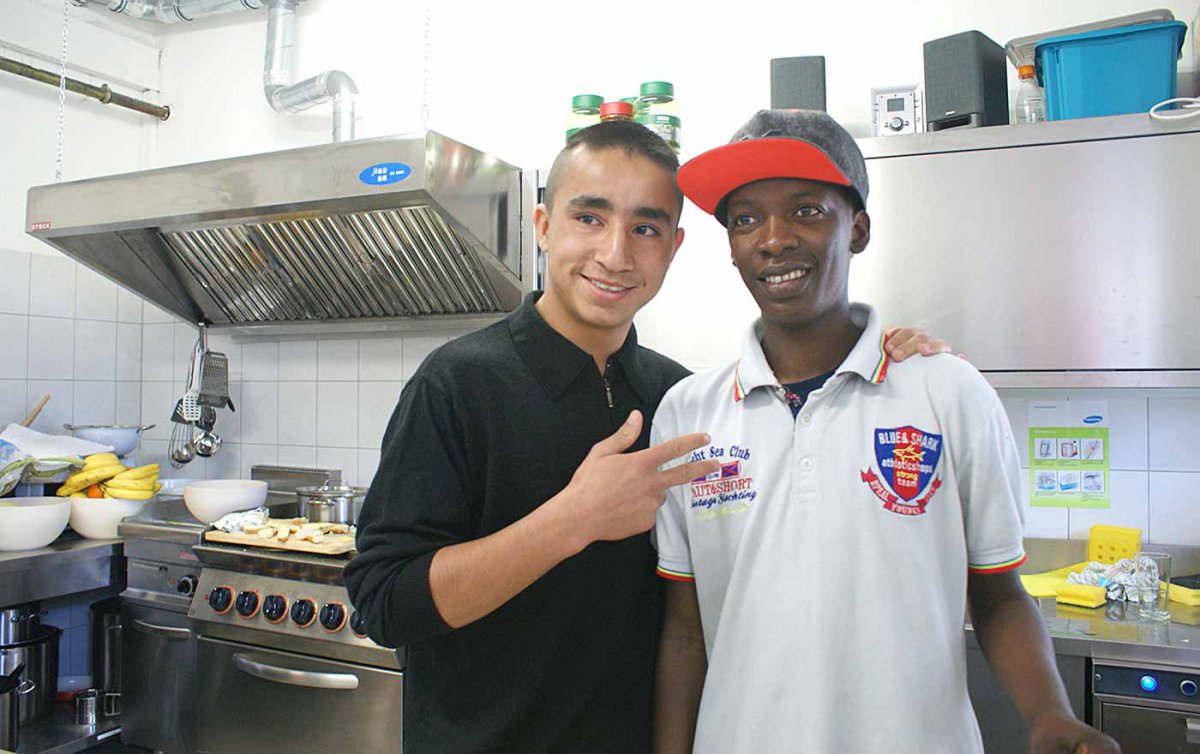 Unbegleitete minderjährige Flüchtlinge haben im „Haus Papageno“ in Wien-Meidling Zuflucht gefunden. Im Bild zwei Bewohner in der Küche des Hauses. Foto: Diakonie/Gasser Zwei Flüchtlingsbuben die in die Kamera schauen, im Hintergrund eine Küche.