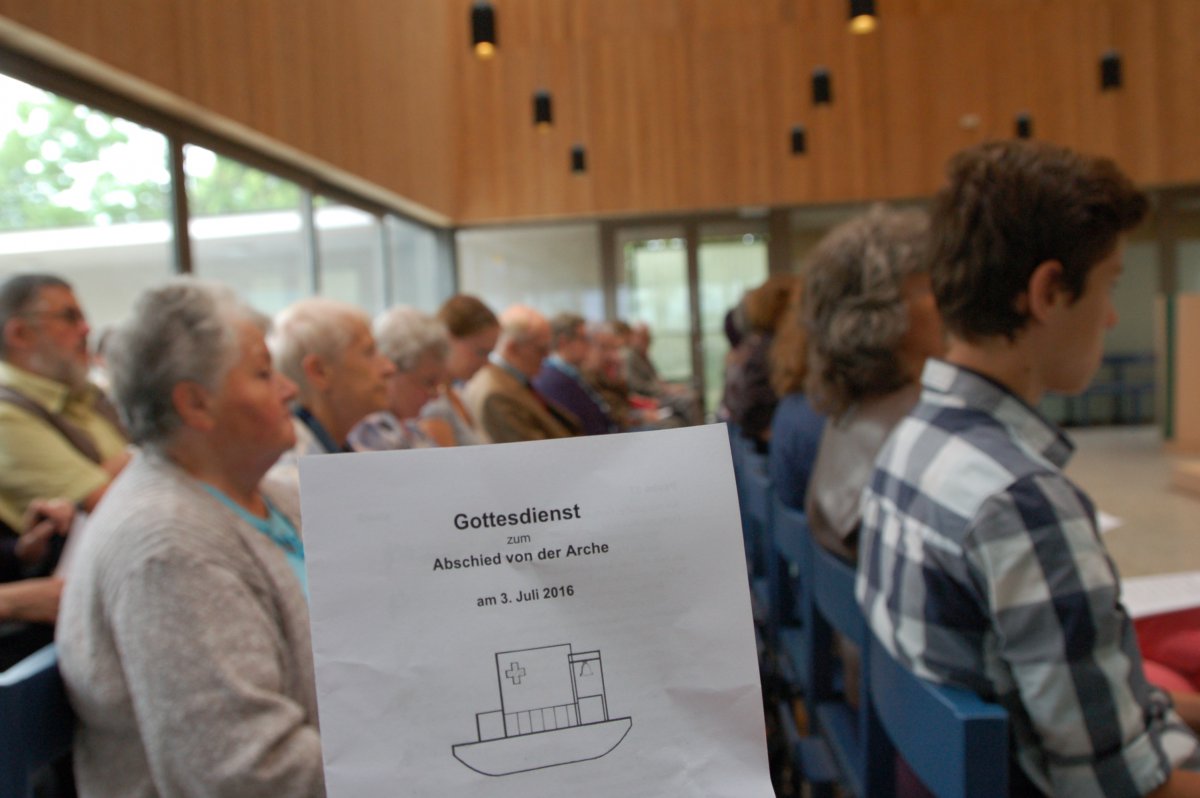 Die "Arche" wird verkauft. Ein Abschiedsgottesdienst ist am 3. Juli gefeiert worden. (c) M. Schomaker Im Vordergrund sieht man den Liedzettel zum Abschiedsgottesdienst, im Hintergrund die vollbesetzte Kirche.