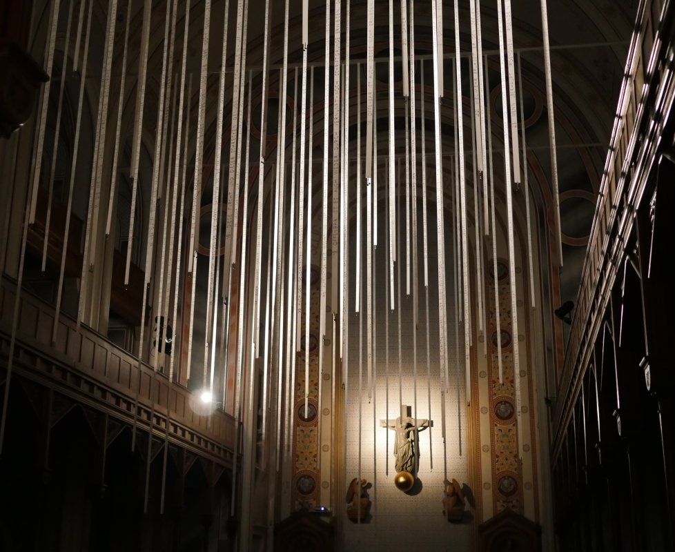 Betritt man die Kirche bei Dunkelheit, werden die Bänder durch eine Videoprojektion bespielt und die Schrift wird deutlich sichtbar. Betritt man die Kirche bei Dunkelheit, werden die Bänder durch eine Videoprojektion bespielt und die Schrift wird deutlich sichtbar.