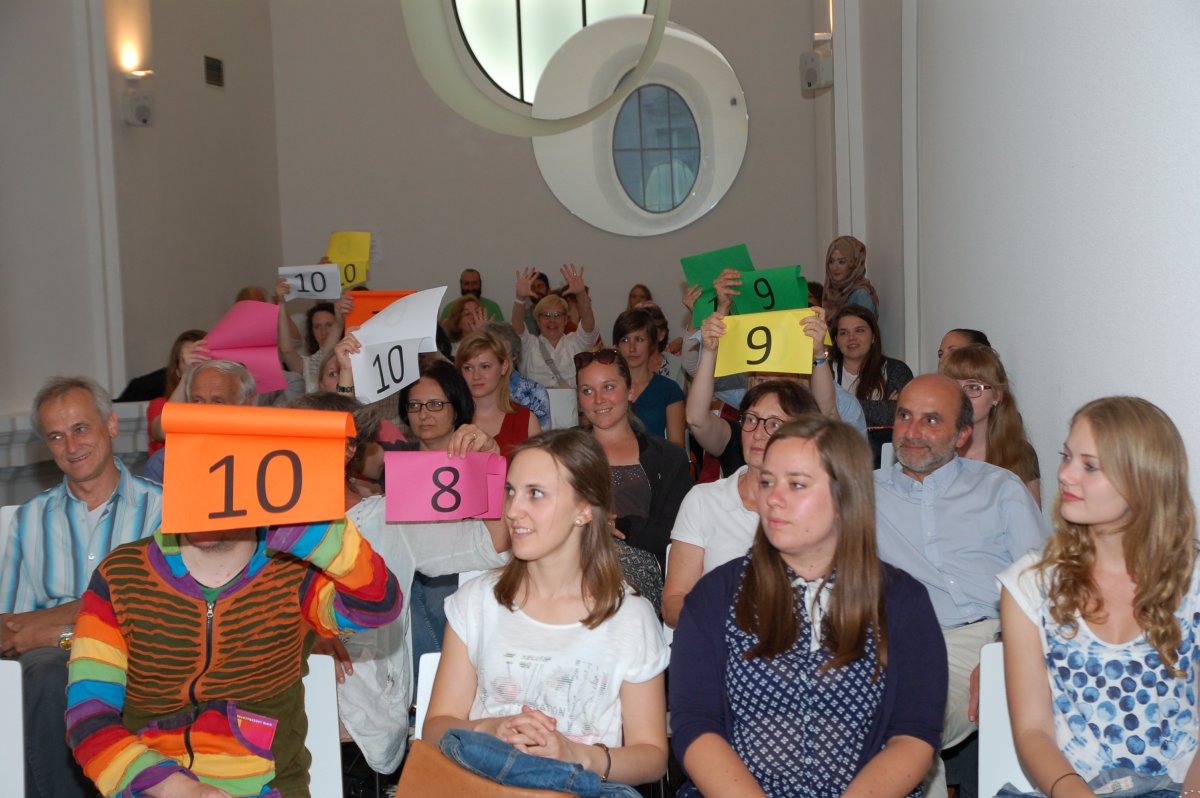 Voting: Beim Preacher Slam bildet das Publikum die Jury. (c) M. Schomaker Menschenmenge, die Punktetafeln in die Höhe halten.