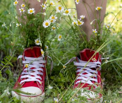 Jugendlicher mit Schuhen und Blumen im Gras